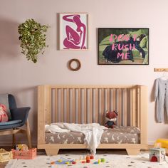 a child's bedroom with pink walls and artwork on the wall, including a baby crib