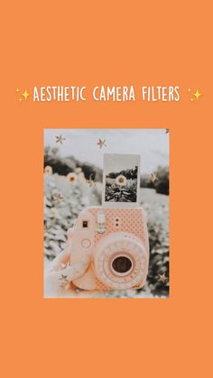 an orange and white polaroid camera sitting on top of a field of daisies