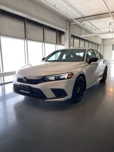 a white car is parked in an empty garage with lots of windows on both sides