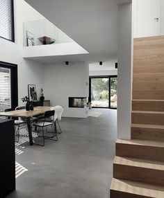 the interior of a modern house with stairs leading up to the second floor and dining area