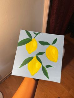 someone is holding up a painting with lemons on it