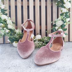 a pair of pink shoes sitting on top of a cement floor next to white flowers