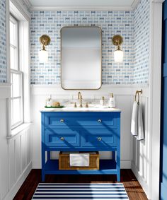 a bathroom with blue and white wallpaper, two sinks and a mirror on the wall