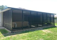 an enclosed patio area in front of a house with a car parked on the grass