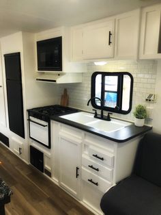 a kitchen with white cabinets and black counter tops in a mobile home or camper