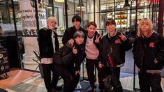 group of young men posing for photo in front of store window with one man giving the thumbs up