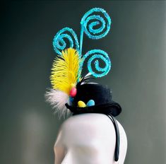 Introducing our captivating Whimsical Swirl Topper Black Hat is adorned with vibrant turquoise sequin spirals, a striking yellow feather, and a cluster of colorful eggs, all set atop a stylish black miniature hat. Age Group/Gender - Adult/Kids/Unisex Size/Type - One size fits all adults and kids Color - Black/Blue Material - Feathers Special Features - Easter eggs Personalization - Not available Adjustable Mini Hats For Carnival And Kentucky Derby, Whimsical Multicolor Adjustable Fascinator, Fun Adjustable Mini Hats For Carnival, Whimsical Adjustable Mini Hats For Carnival, Whimsical Mini Hats For Carnival And Kentucky Derby, Masquerade Mask Women, Colorful Eggs, Yellow Feathers, Fascinator Hat