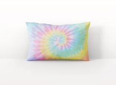 a colorful tie - dyed pillow on a white surface with a light blue back ground