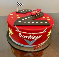 a red cake with cars on it sitting on top of a table