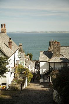 an alley leading to the ocean with people walking down it and houses on either side