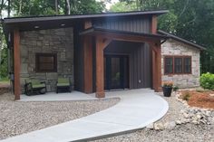 a small house with a large patio and stone walkway leading to the front door is surrounded by trees