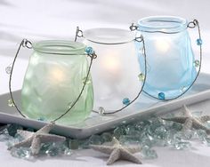 three glass jars with lights on them are sitting on a tray surrounded by starfish