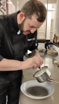 a man standing in a kitchen pouring something into a bowl with a ladle on it