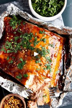 a piece of meat covered in sauce and garnished with parsley next to a bowl of salsa