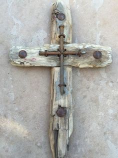 a cross made out of driftwood on the ground with rusted metal rivets