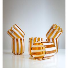 four orange and white striped vases sitting on top of a table next to each other