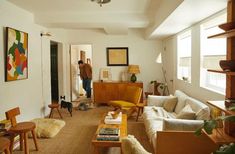 a living room filled with lots of furniture and a man standing in the doorway behind him