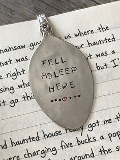 a silver necklace with writing on it that says fell asleep here and has a heart in the middle