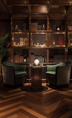 two chairs sitting in front of a table with books on the shelves behind them,