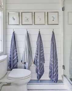 three towels hanging on the wall next to a toilet