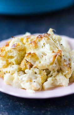 a pink plate topped with mashed potatoes on top of a table