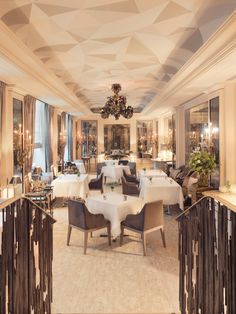 a dining room with tables, chairs and chandeliers