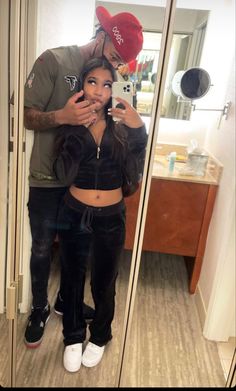 a man taking a selfie in front of a mirror with a woman standing next to him