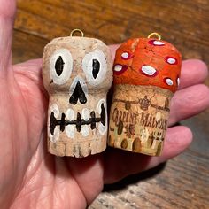 there is a hand that has two small skulls on it, one with a bottle cap and the other with a skull