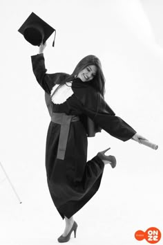 a woman in graduation gown and cap jumping up into the air