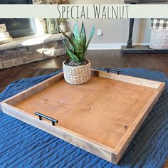 a wooden tray sitting on top of a blue rug next to a potted plant