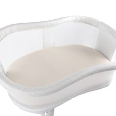 an infant crib that is white and has a pillow on the top of it