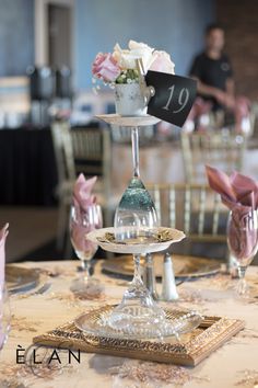 the table is decorated with pink and white flowers in glass vases on pedestals