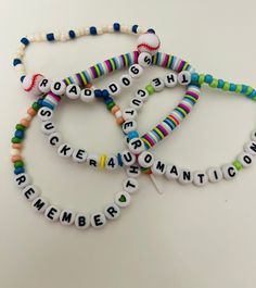 three bracelets with words written in different colors and letters on them, all made out of plastic beads