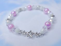 Introducing the must-have accessory of the season - a stunning elastic bracelet crafted with a combination of iridescent white acrylic beads, shimmering silver accent charms, and dainty glass beads. The centerpiece of this piece is a beautiful star charm that adds a touch of elegance and sparkle. The color scheme of white iridescent, violet, and silver gives this bracelet a unique and feminine look, perfect for any dolly, coquette, or angel core style. With its elastic design, this bracelet is e White Stretch Bracelet With Faceted Beads For Party, Adjustable White Charm Bracelet With Star Charm, Adjustable White Star Charm Bracelet, White Star Bracelets For Party, White Star-shaped Party Bracelets, Dolly Coquette, Cute Beaded Bracelet, Angel Core, Diy Kandi Bracelets