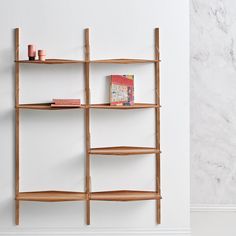 a wooden shelf with books on it against a white wall