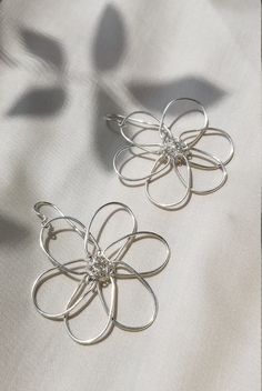 Flower power! Bold, floral wire earrings inspired by summer daisies. Stand out from the crowd with these fun statement pieces. Simple yet stunning. Lightweight, shiny, and perfect for long wear. Made by hand from your choice of silver or gold plated wire. The flower center is wrapped with either .999 fine silver wire or fine gold wire.  Ear hooks are either .925 sterling silver or gold fill, so this design may be enjoyed by sensitive ears. Earrings measure approx. 2 inches across. Drop is 1.5 in Droopy Flowers, Wire Flower Earrings, Wire Flowers, Flower Center, Floral Wire, Gold Wire, Wire Earrings, Sensitive Ears, Silver Wire