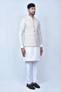 Cream bundi in with floral embroidered patterns. Comes with off white kurta and pant.
Components: 3
Pattern: Embroidered
Type Of Work: Floral Patterns
Neckline: Mandarin Collar
Sleeve Type: Bundi: Sleeveless, Kurta: Cuff Sleeves
Fabric: Kurta and Pant: Art Silk, Bundi: Art Silk Jacquard
Color: Cream, Off White
Other Details: 
Front carved button bundi
Welt pocketed bundi
Elasticated pant waistband
Occasion: Wedding - Aza Fashions Pant Art, Sleeveless Kurta, Payal Singhal, Jayanti Reddy, Embroidered Patterns, Anushree Reddy, Anamika Khanna, Diana Penty, Eid Party