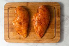 two pieces of chicken on a cutting board