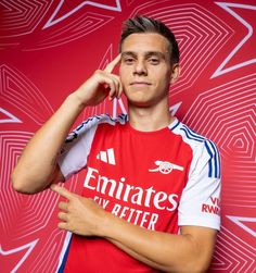 a soccer player poses for a photo in front of a red background