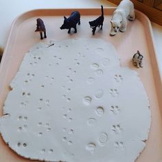 there are many small plastic animals on the play tray with water and sand in it