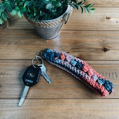 a crocheted keychain sitting on top of a wooden table next to a potted plant