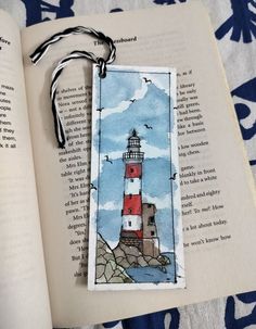 an open book with a red and white light house on it next to a blue flowered towel