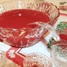 a glass bowl filled with red liquid on top of a table next to other dishes