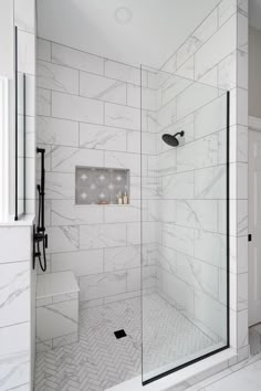 a walk in shower sitting next to a white tiled wall and floor with a glass door