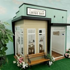 a miniature coffee shop with benches and flowers on the grass in front of it's entrance