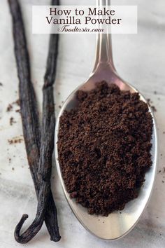 a spoon filled with cocoa powder next to an unpeeled vanilla