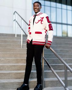 a man standing on some steps with his hands in his pockets and wearing a jacket