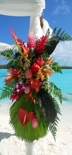 a bouquet of flowers on the beach with blue water in the background