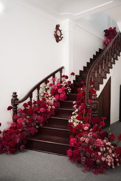 a staircase with flowers on the steps and a clock hanging on the wall next to it