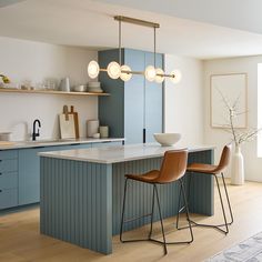 a kitchen with two stools next to an island in front of a counter top